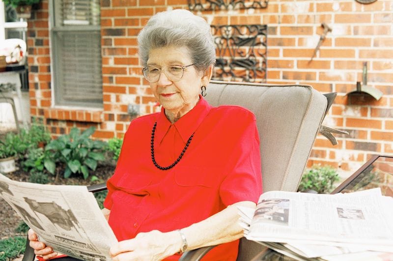 Senior Woman Reading Newspaper Patio